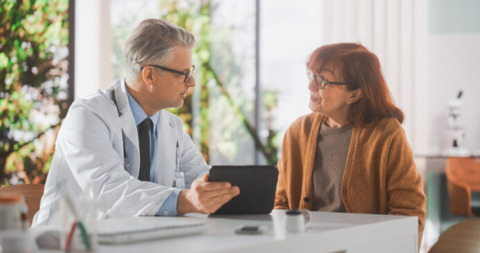 Clinician and patient discussing with a tablet.